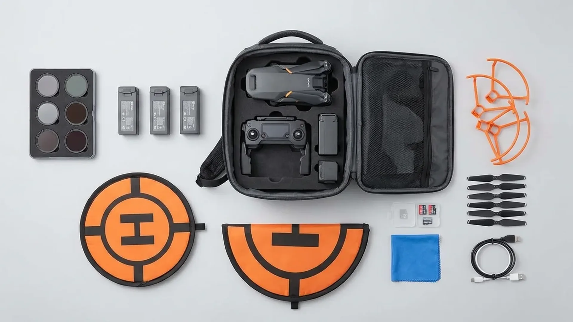Essential drone accessories laid out including extra batteries, ND filters, carrying case, and protective gear for DJI Mini 4 Pro