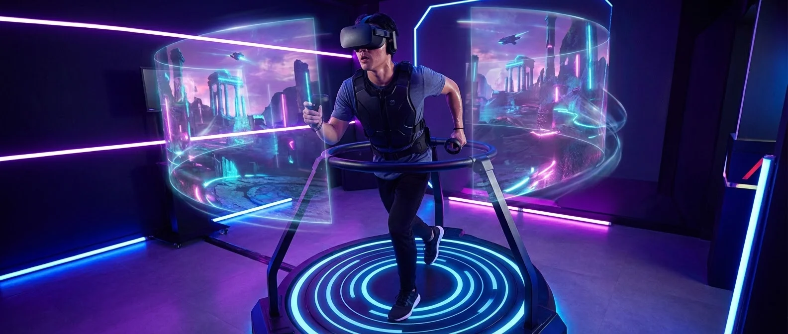 Person walking on Virtuix Omni One VR treadmill while wearing VR headset in modern gaming setup